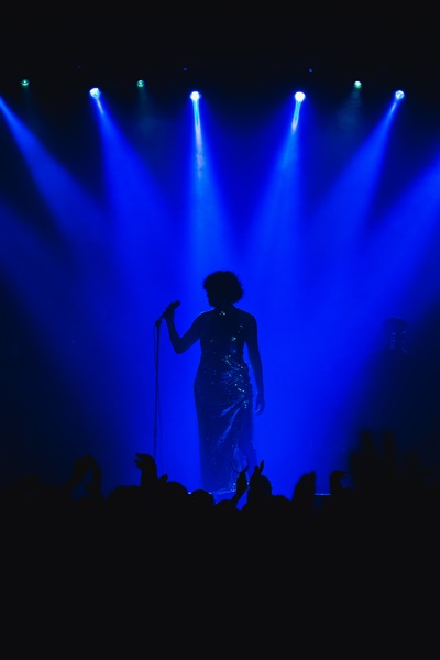 Foto de Luedji Luna na penumbra com luz azulada